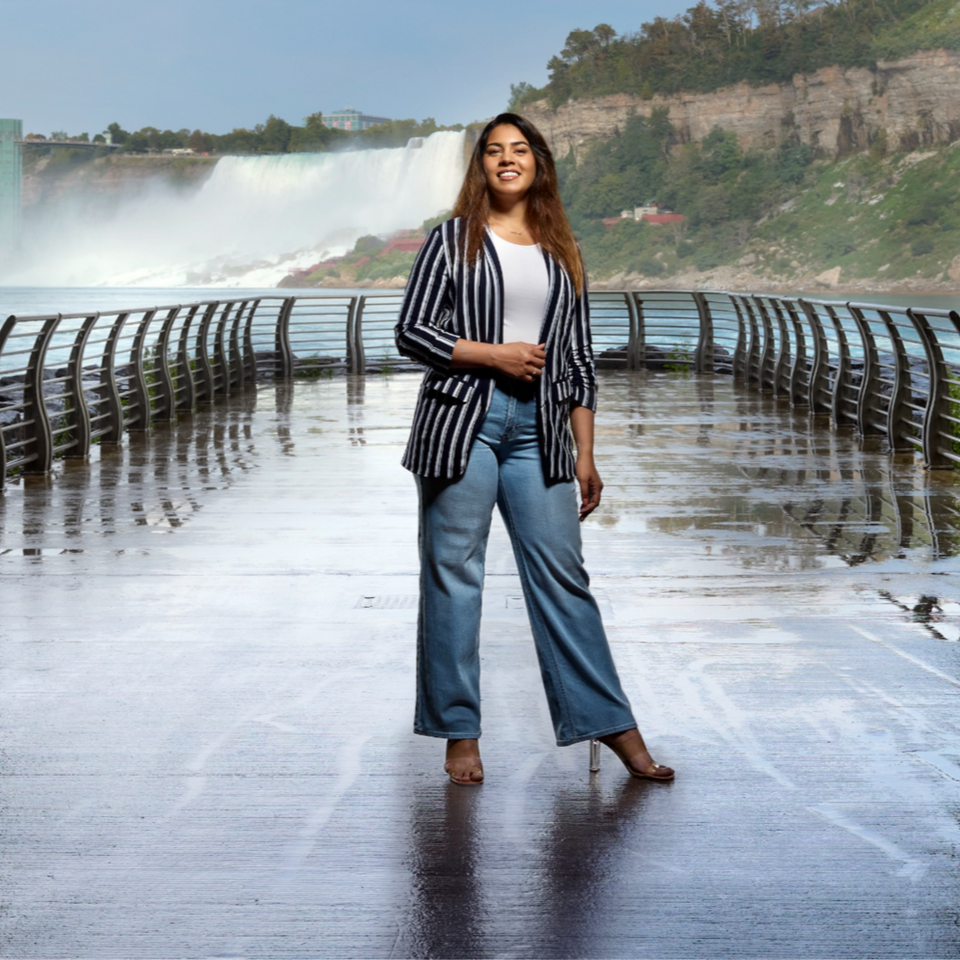 Woman stands confidently with Niagara Falls in the background for a photo.