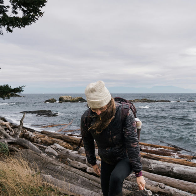 Woman walks along the beach near the water, enjoying the cloudy scenery