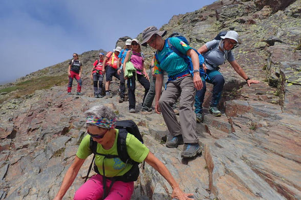 Grup d'excursionistes baixant per una zona de roques llises a l'alta muntanya