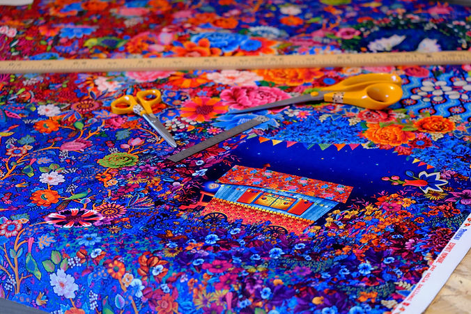 préparation découpe tissu multicolor dominante bleu orange avec motif fleur et roulotte dans la nuit