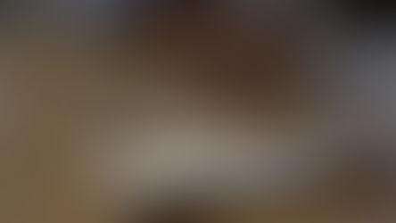 Hand reaching for a folder on a wooden desk, with blurred keyboard in background. Text: "Hartmann Rhodes: How to Sell Your Business Confidentially."