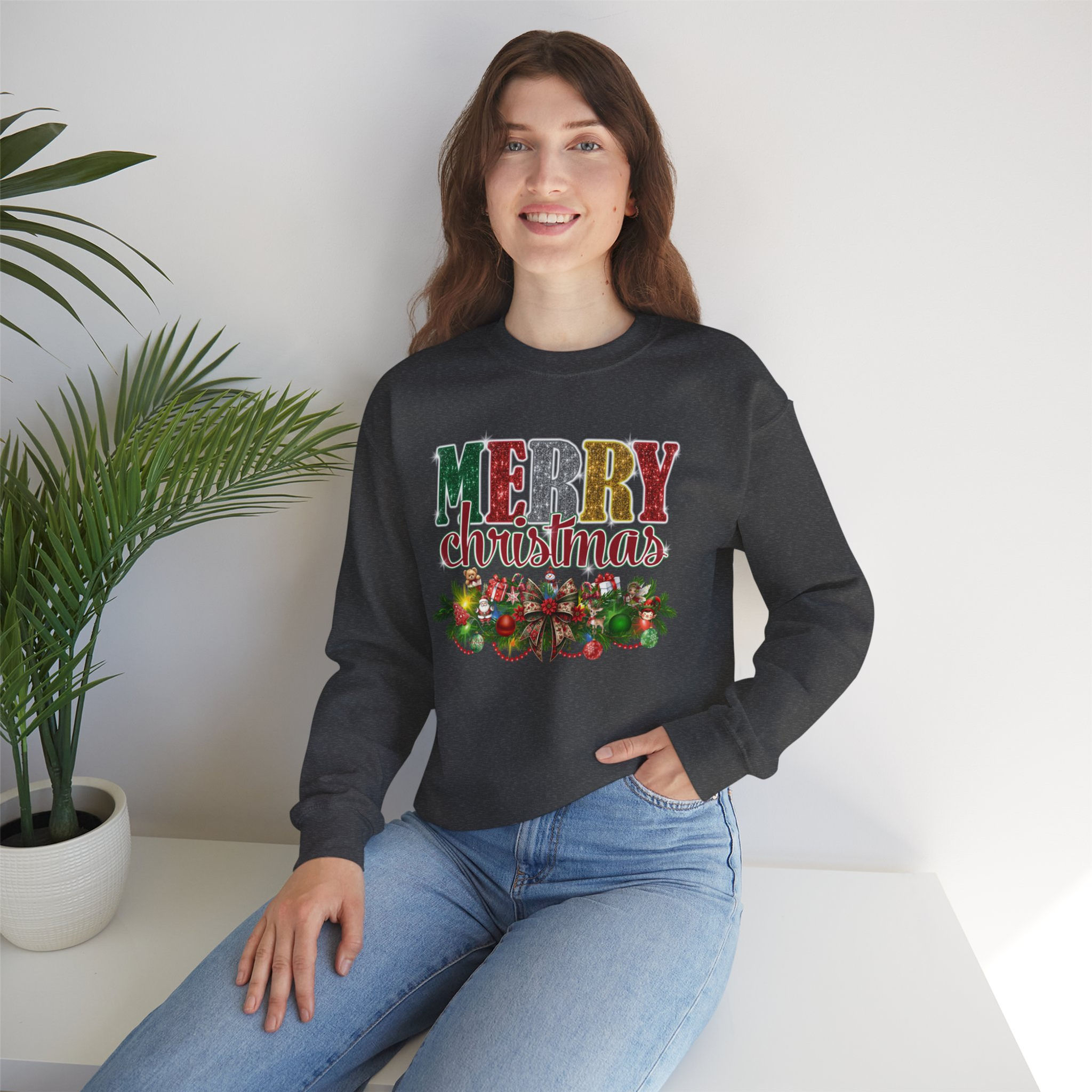 Woman wearing "MERRY CHRISTMAS" sweatshirt smiling, with background of plant.