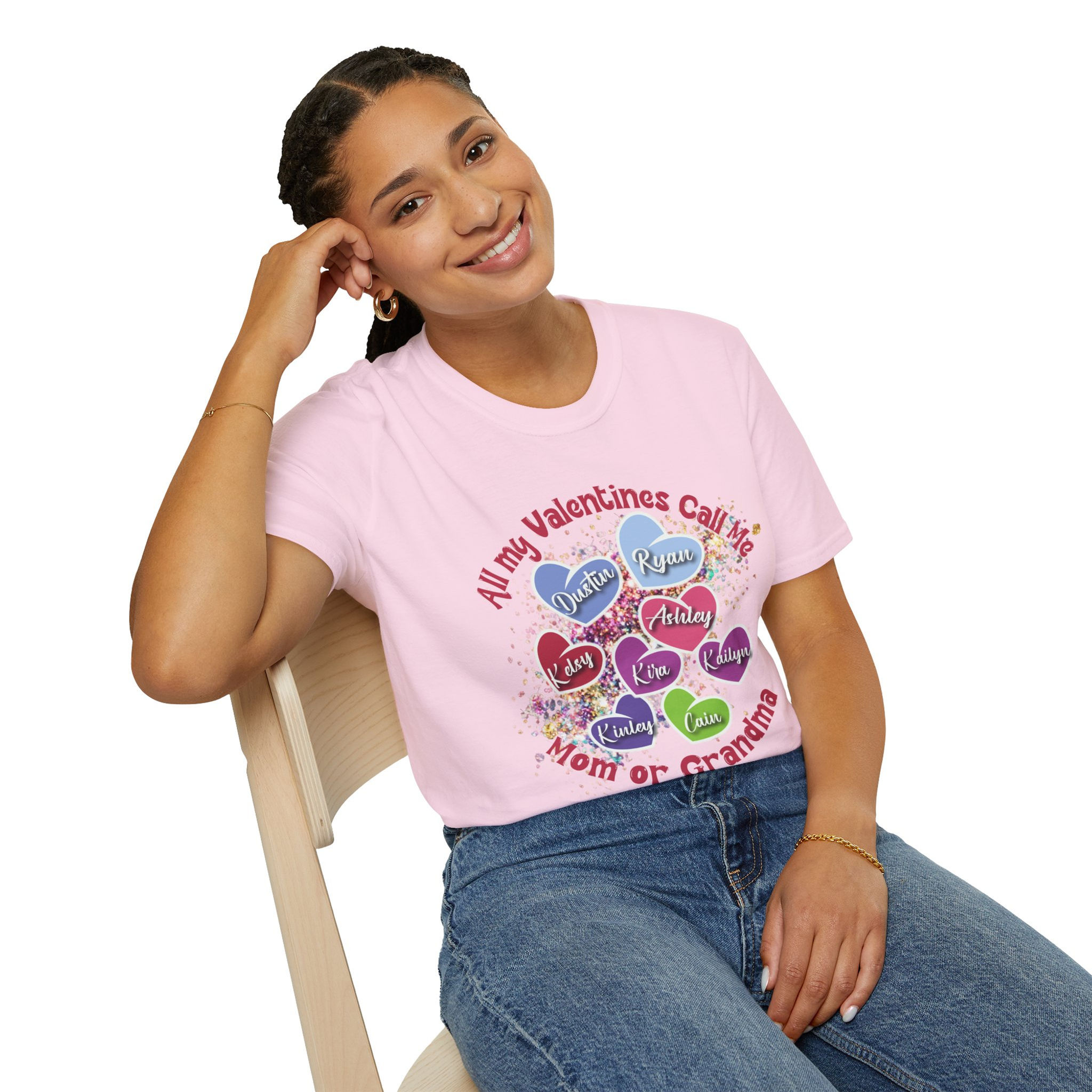 Smiling woman wearing pink shirt with 'All my Valentines...' text sitting on chair.