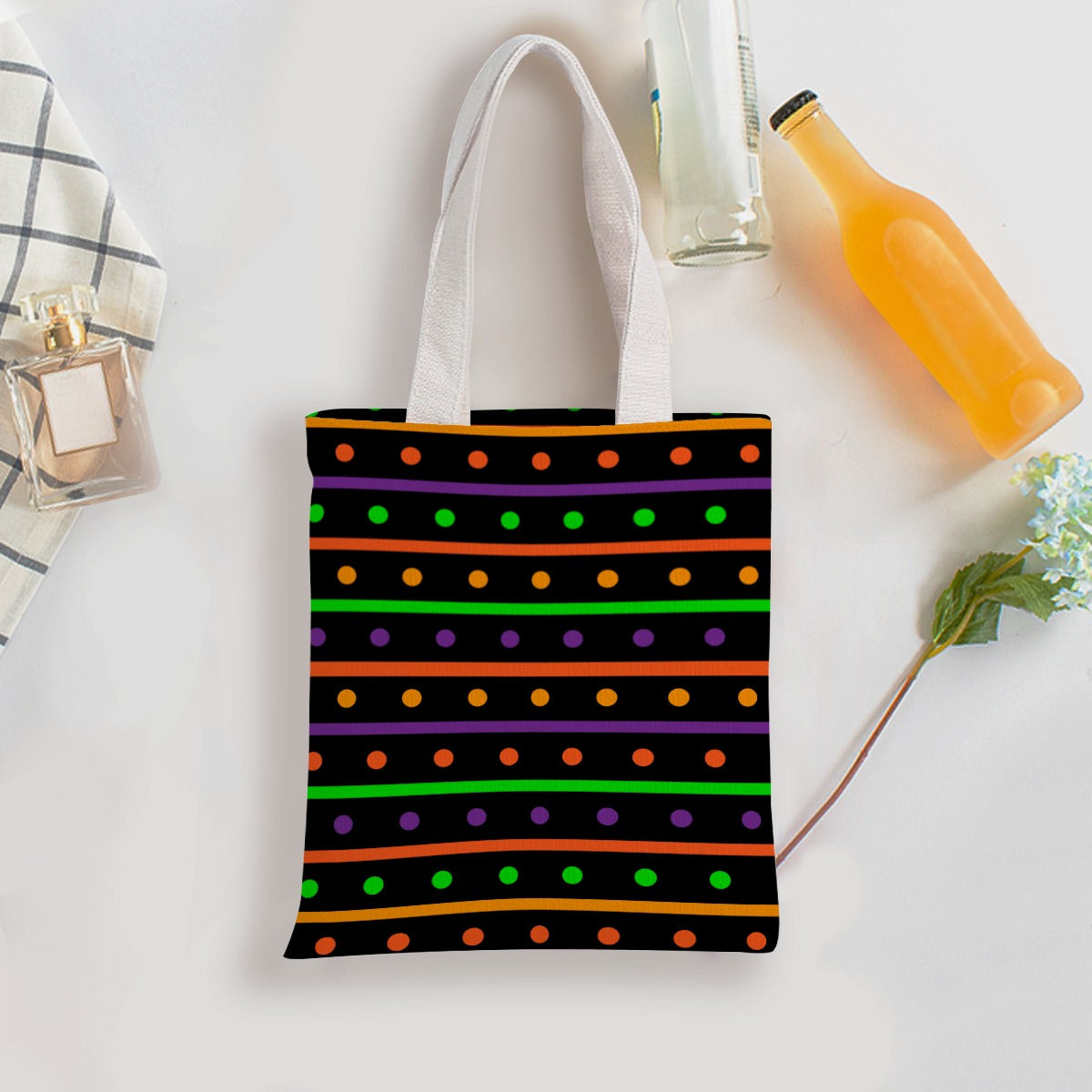 Black tote bag with colorful Halloween stripe pattern design on white surface