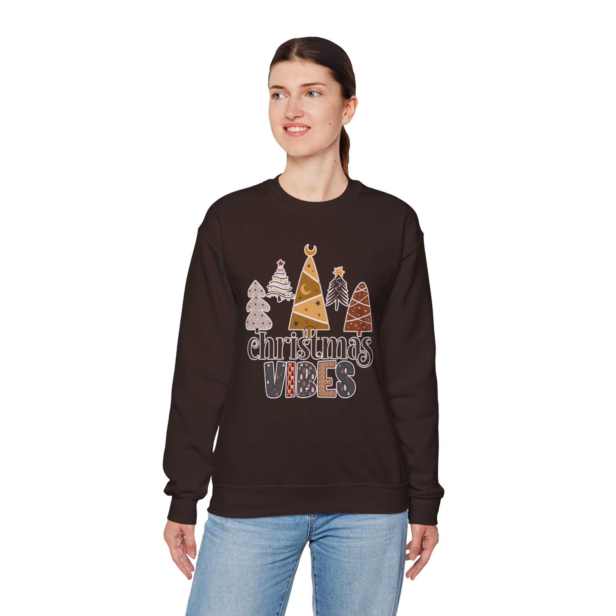 Woman wearing brown sweatshirt with Christmas Vibes graphic and boho trees.