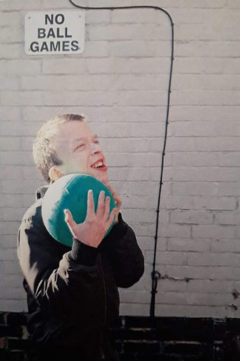 Connor being very cheeky holding a ball in front of a no ball games sign