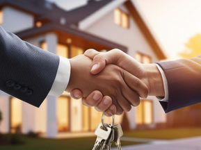 Two people shaking hands, exchanging keys in front of a house.