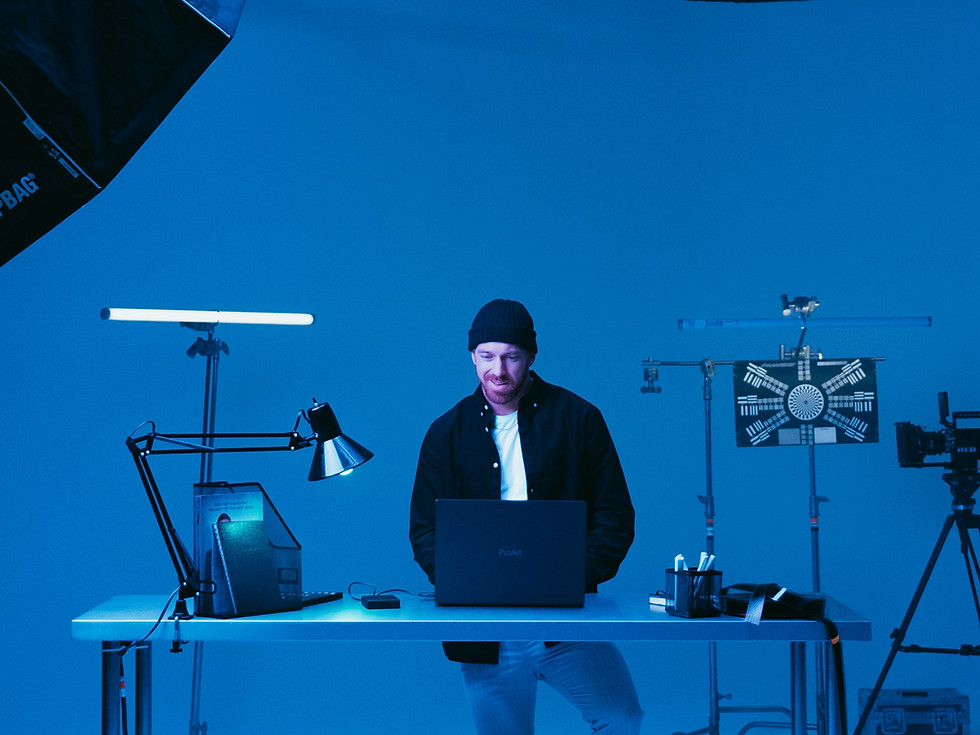 Man working on laptop in a blue lit studio environment.