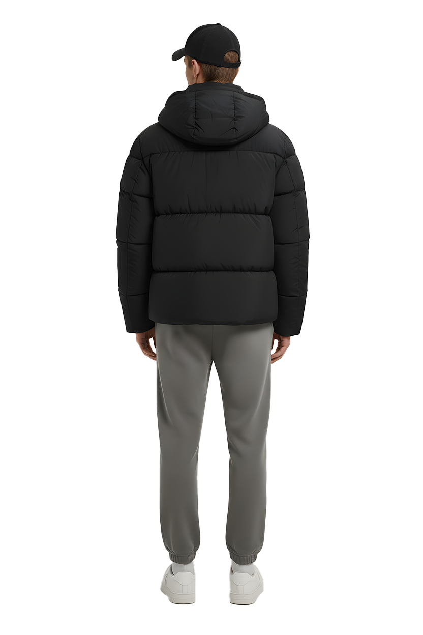 Man stands wearing black puffer jacket, gray pants, and white sneakers.