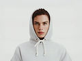 Young man wearing a gray hooded sweatshirt, posing for a portrait.