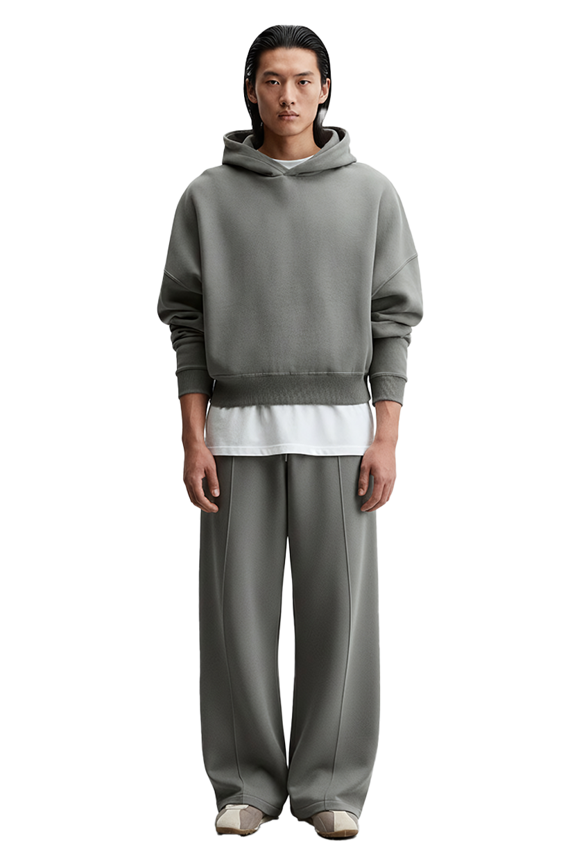 Man wearing gray hoodie and pants with white Drift Layer tee on black background.