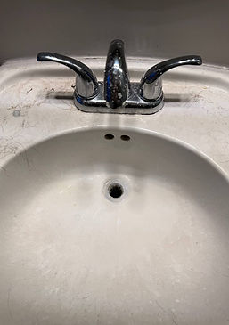 Dirty bathroom faucet and sink before cleaning — water spots and grime visible.