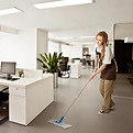 Efficient office cleaning Woman tidying up living room in a sunlit modern apartment