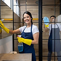 Comprehensive Airbnb Cleaning Smiling cleaner holding cloth and cleaning spray in residential setting