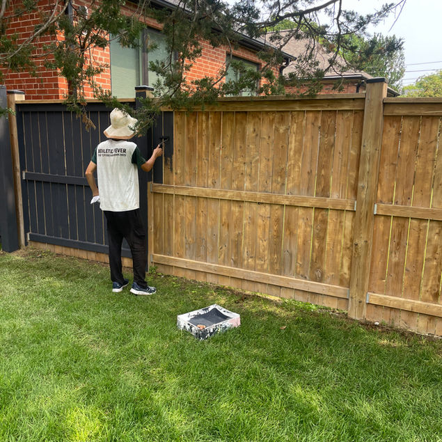Spraying a solid-stain to the fence