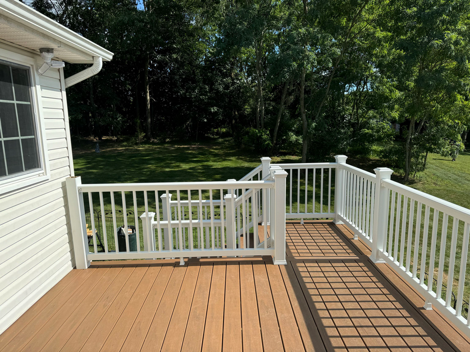 Wooden deck with white railings and stairs to a grassy yard
