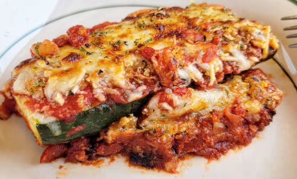 Baked Zucchini Parmesan on a white plate with melted cheese and tomato sauce, garnished with herbs, creating a warm, appetizing look.