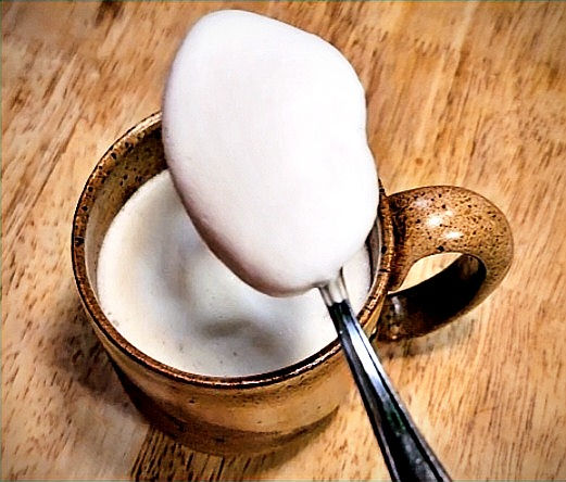 a heaping spoonful of milk foam over the top of a cup of tea