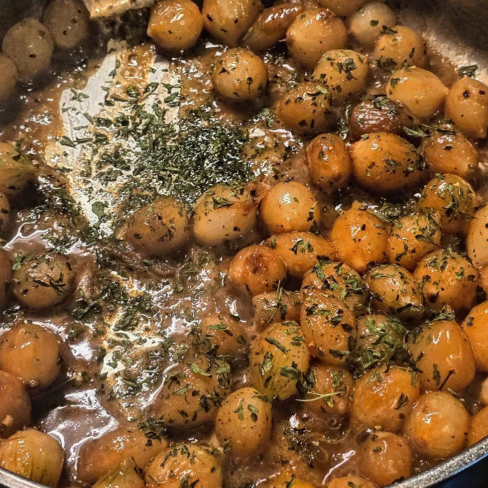 Brainsed pearl onions in a stainless steel pan garnished with green parsley flakes