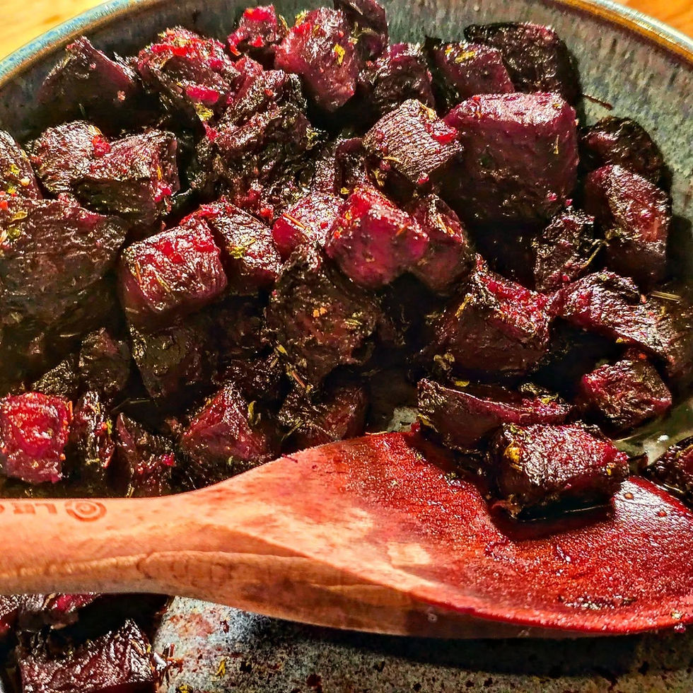 A serving bowl filled with air fryer roasted beets with lemon and thyme with a wooden spoon