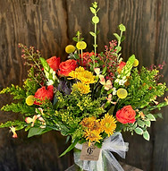 This Image is of a beautfiful Fall colored vase arrangemt in yellows and oranges with greenery and orange roses.