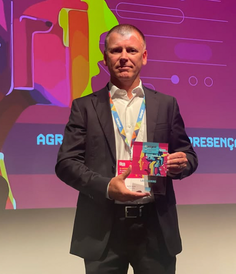 Delfim Dores, COO do LAS Group, segura o Prémio Co-Inovação 2024 da Quidgest em nome da CEO Luísa Caldeira, durante o Q-Day Conference na Culturgest, Lisboa – reconhecimento pela inovação na formação aeronáutica.