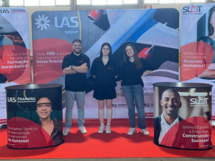 Três representantes da LAS Group no stand da empresa durante o Beja Air Show 2024, evento aeronáutico em Portugal, promovendo formação técnica em aviação.