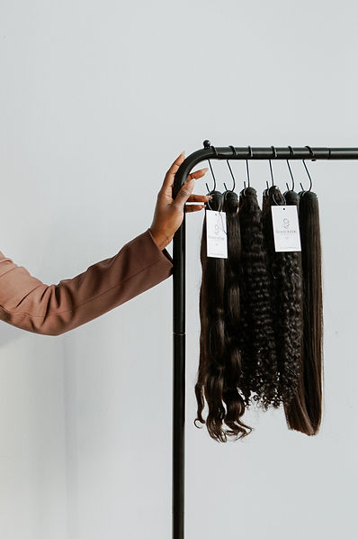 Hand selecting various styles of luxury wigs from a rack