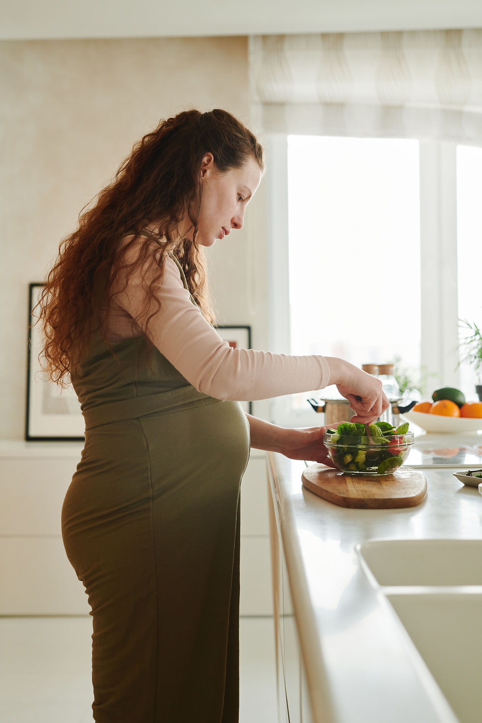 Schwangere bereitet in der Küche einen Salat zu