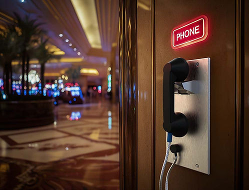 An der Wand montiertes, vandalensicheres Parabit-Telefon mit beleuchteter Beschilderung in einem Casino-Flur für eine sichere Kommunikation zwischen Gästen und Personal.