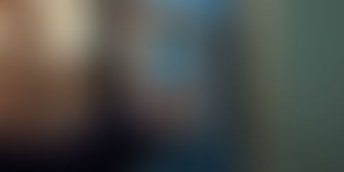 Eine Hand mit einem Finger berührt einen biometrischen Leser mit einem Parabit-Gehäuse, der an einer Wand befestigt ist, hinter der Herbstlaub zu sehen ist