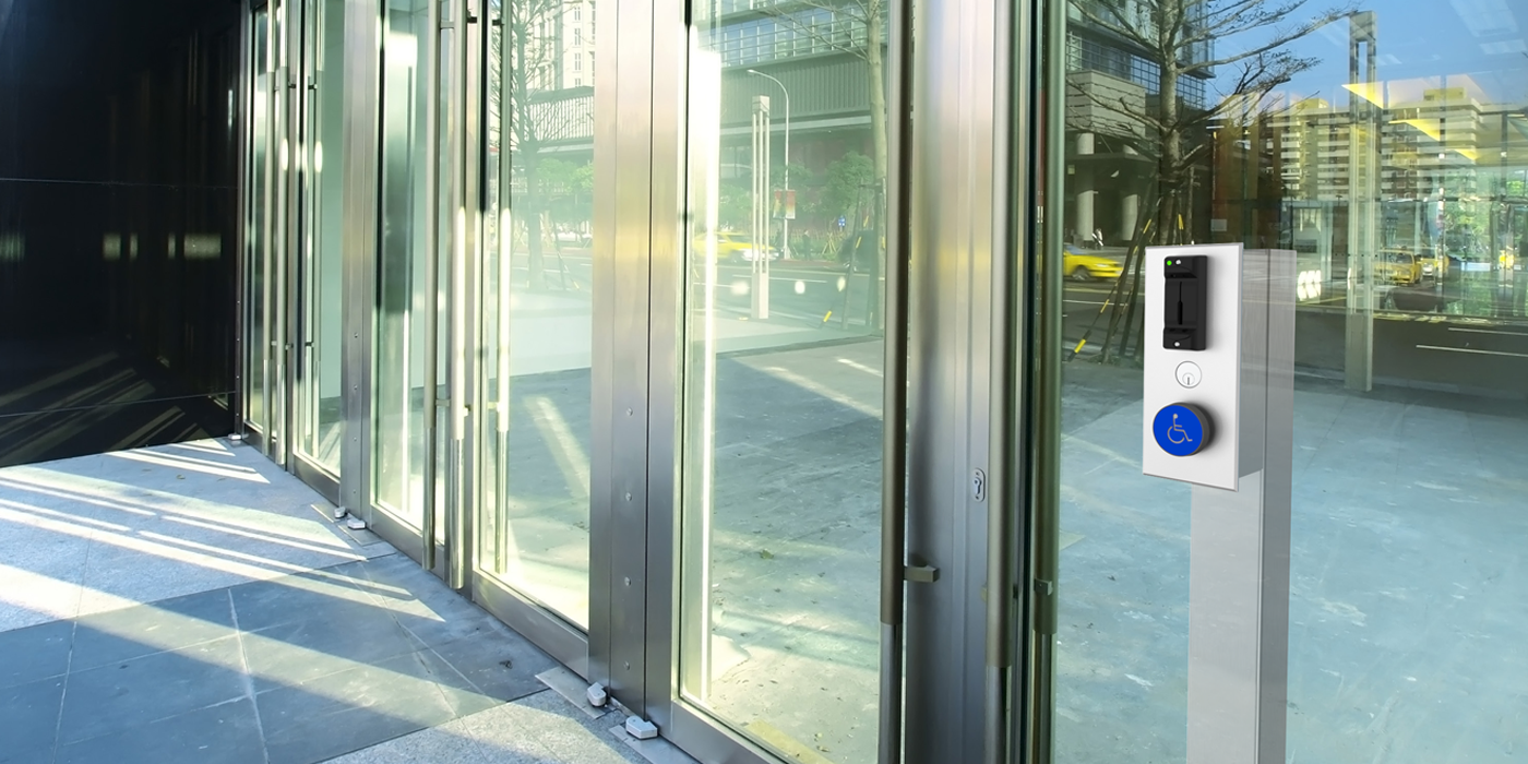 Automatic glass doors with mounted ADA push-to-open switch and integrated access control reader at a public building.