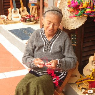 Elderly lady working on a crocheted ornament at an outdoor market