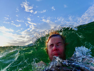 a man in the surf hit by a wave