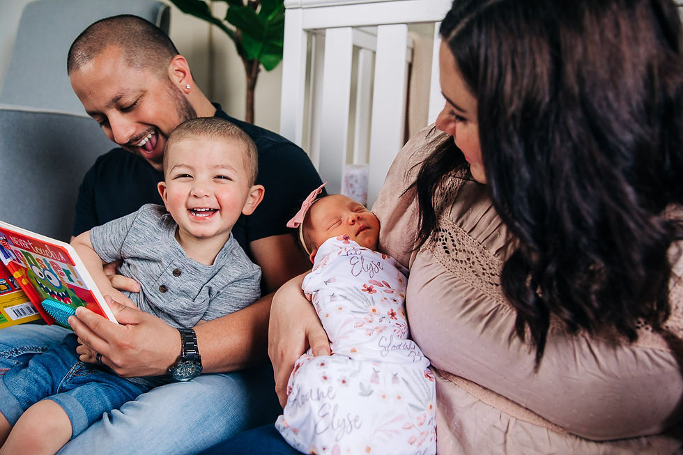 Family photographers in Hartford, Wisconsin capturing a family reading a story to little boy while holding newborn baby girl
