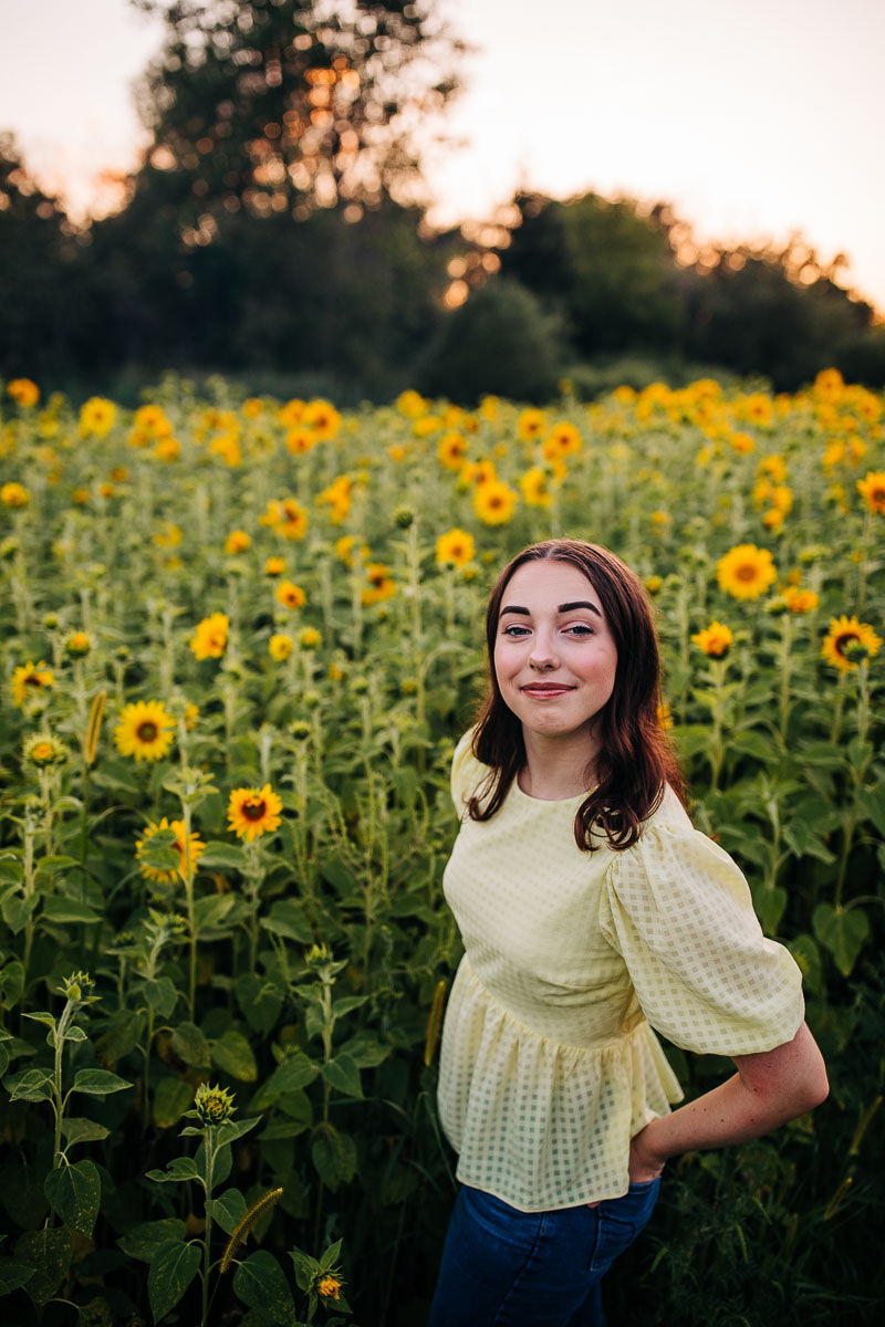 West Bend East High School senior posing in a field of sunflowers at sunset for her senior portrait session