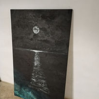 Una visión nocturna de la Luna llena sobre cielo parcialmente nuboso y su reflejo sobre el mar con transparencias de las rocas bajonla luz de una farola en la costa y la propia luz de Luna