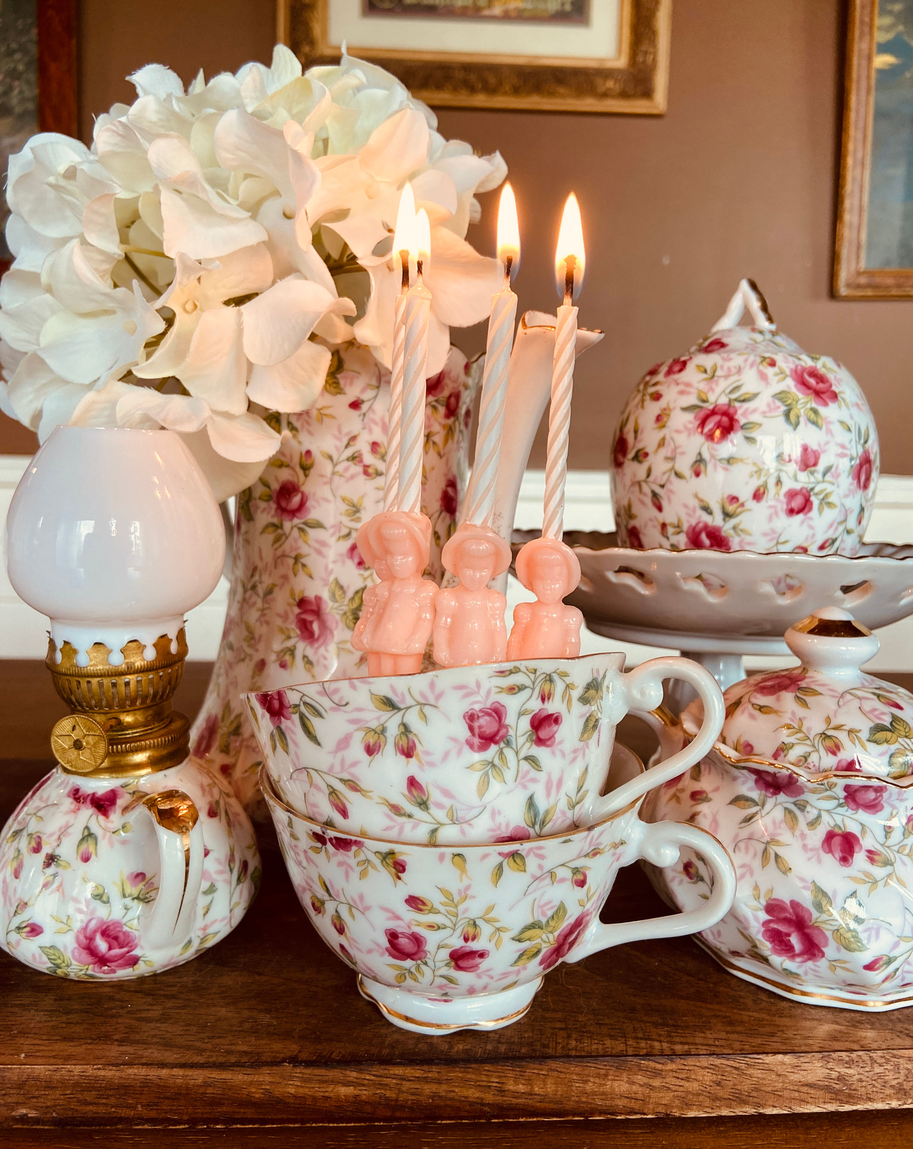 Rose-patterned tea set with lit candles and white flowers