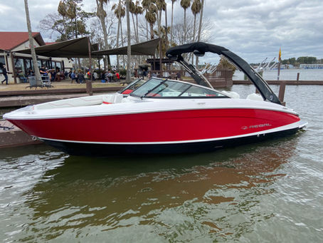 Red-and-white Regal speedboat docked at a waterfront restaurant, with people dining under awnings and palm trees nearby.