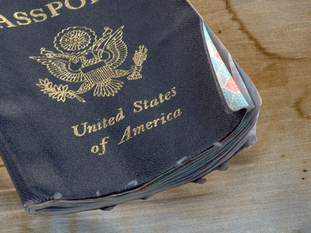 A tattered and worn old passport rests on a wooden surface, its faded pages and creased cover bearing the marks of countless journeys and stories of travel.