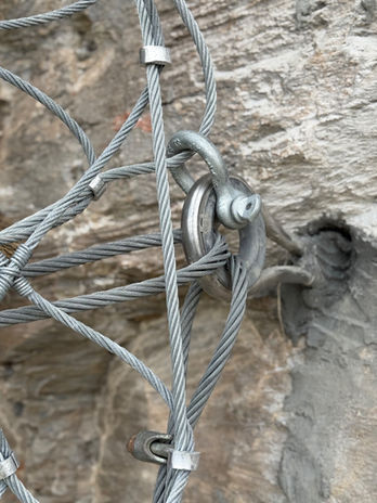 Detail einer Verbindung zwischen Seilanker, Stahlseilen und Sicherungsnetz.