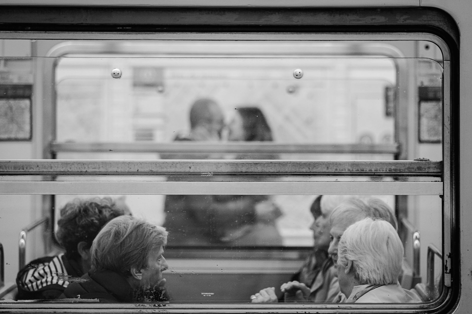 Photo de rue, couple qui s'embrasse en fond avec une rame de métro au 1er plan