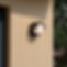 A modern outdoor wall light with a rounded design casts a warm glow on a textured beige wa
