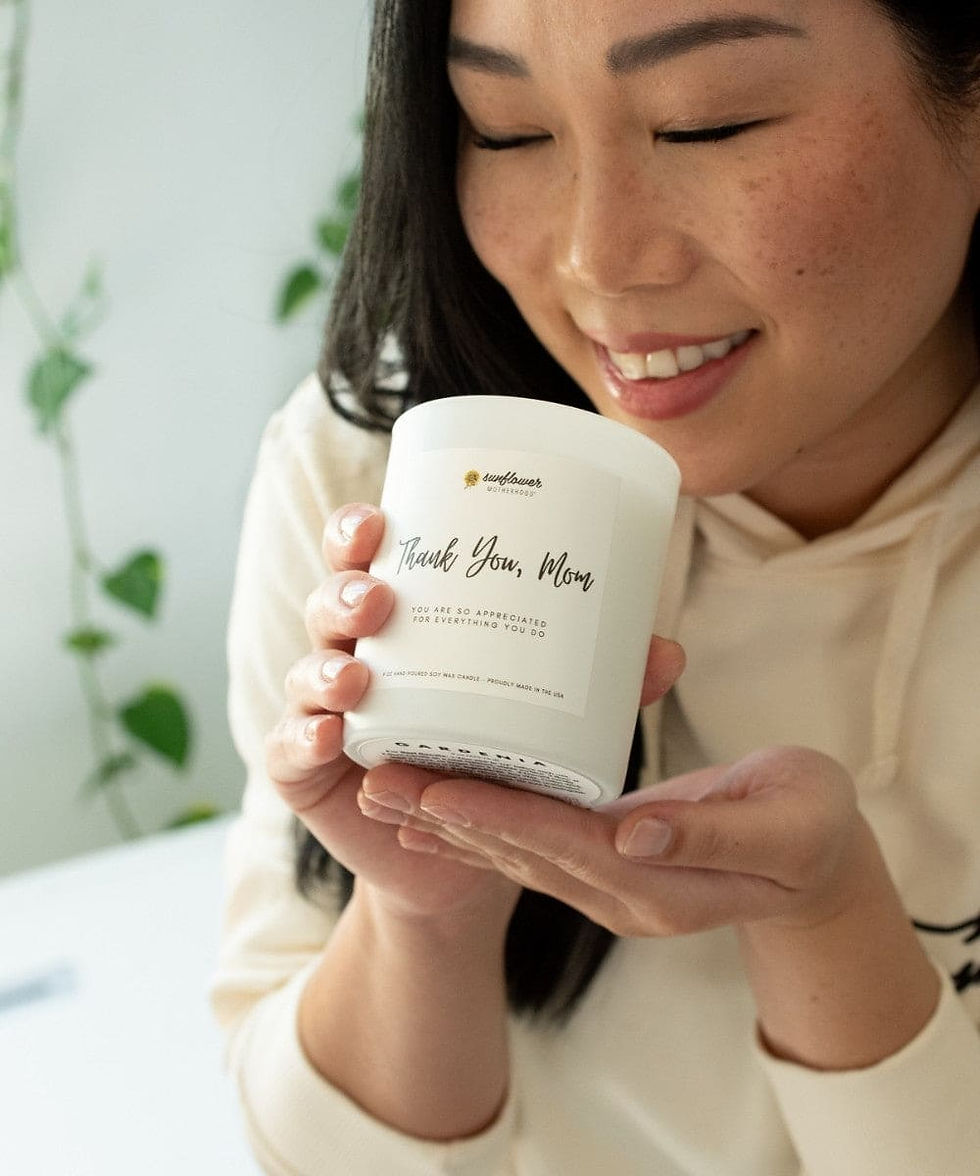 Smiling woman smelling a 'Thank You, Mom' candle