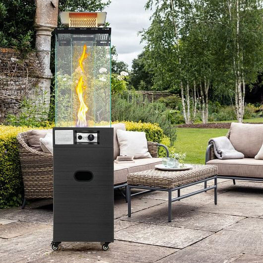 Black propane patio heater with flame on outdoor patio
