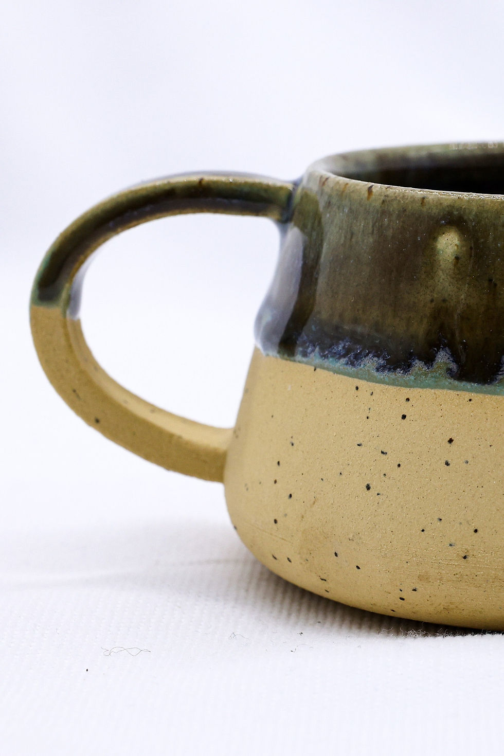 Speckled ceramic mug, tan base, green rim
