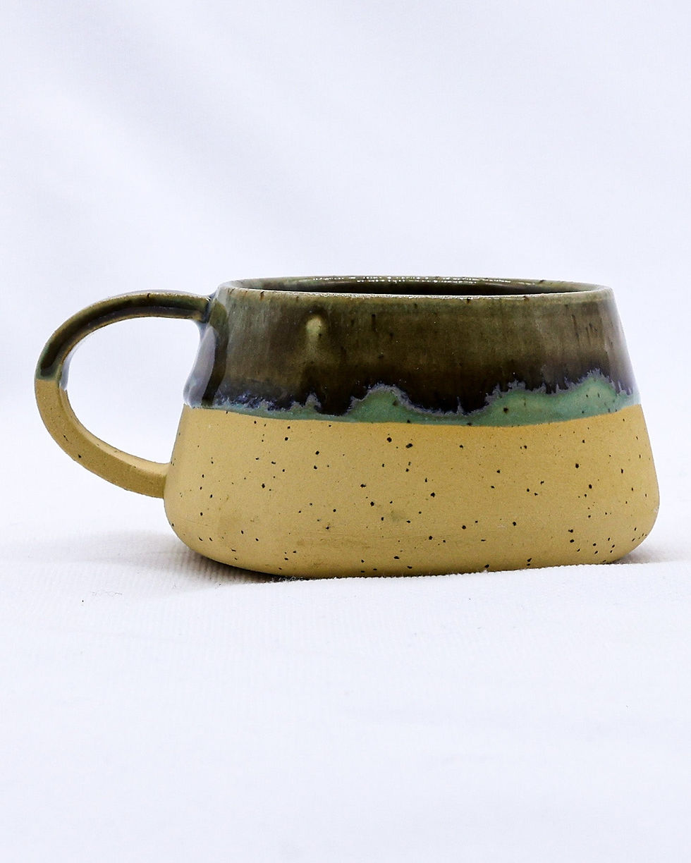 Ceramic mug with speckled tan base and dark green glaze