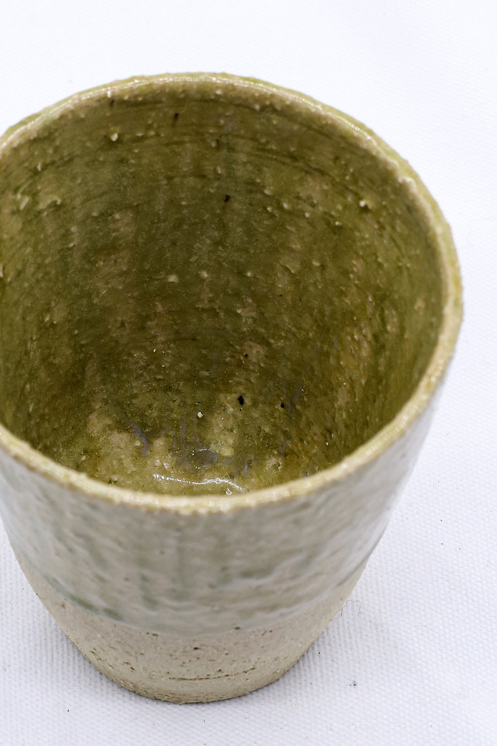 Rough textured ceramic cup with green-brown glaze