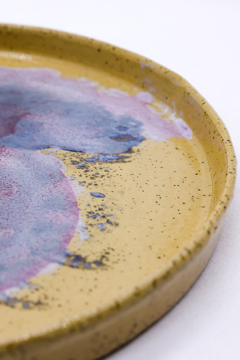 Round speckled yellow plate with abstract blue and pink