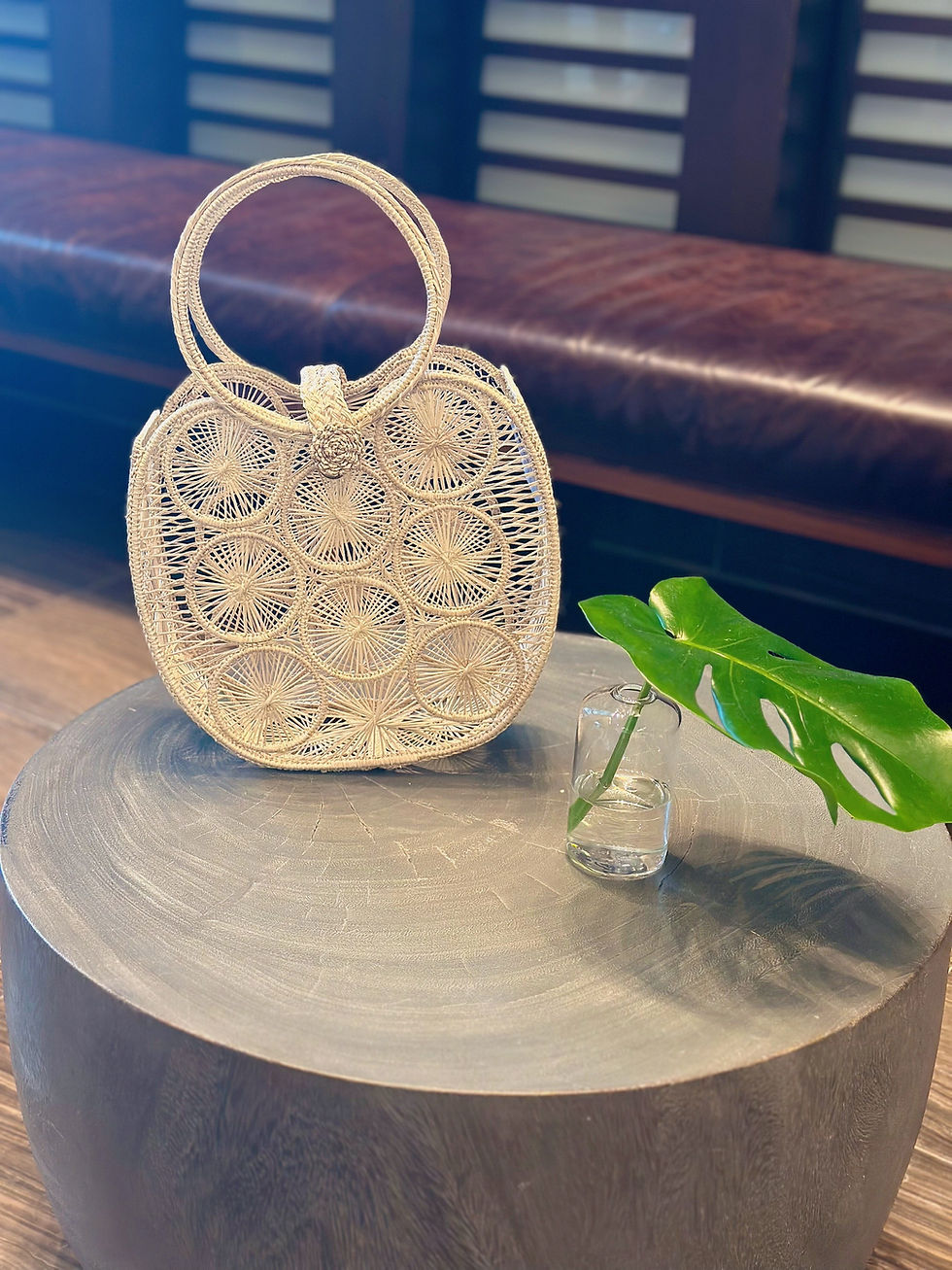 Woven handbag on a table with a green leaf